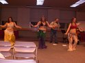Three belly dancers perform to live music.