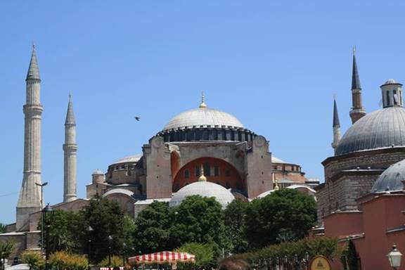 A large building with a dome with Hagia Sophia in the background

Description automatically generated